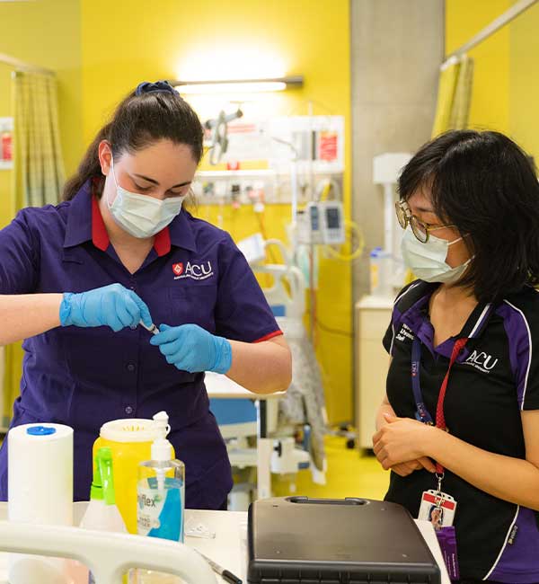 Two ACU students look at a folder while assisted by an instructor in a clinic facility